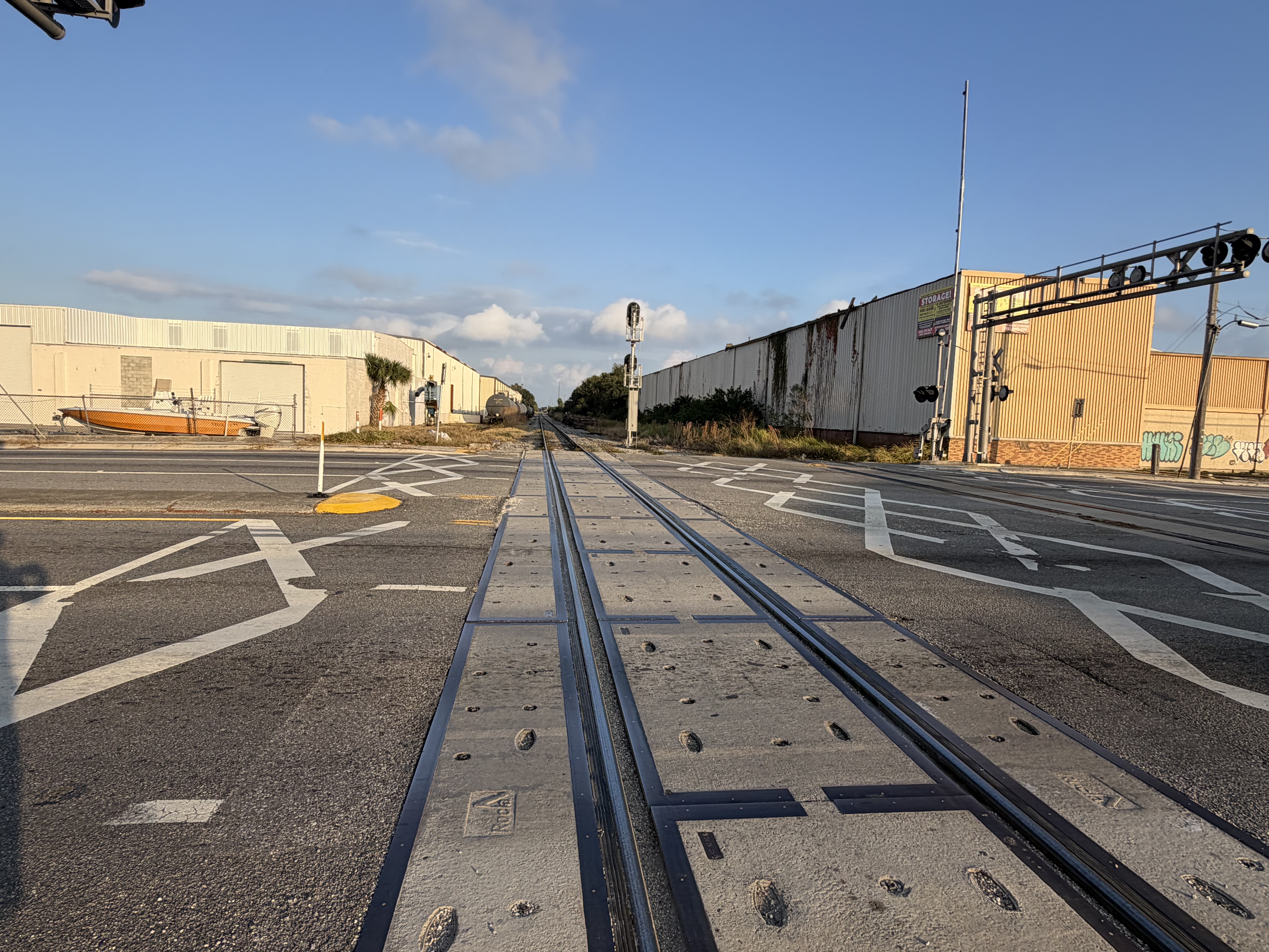 Industrial area grade crossing with rail tracks, road markings, and signal equipment