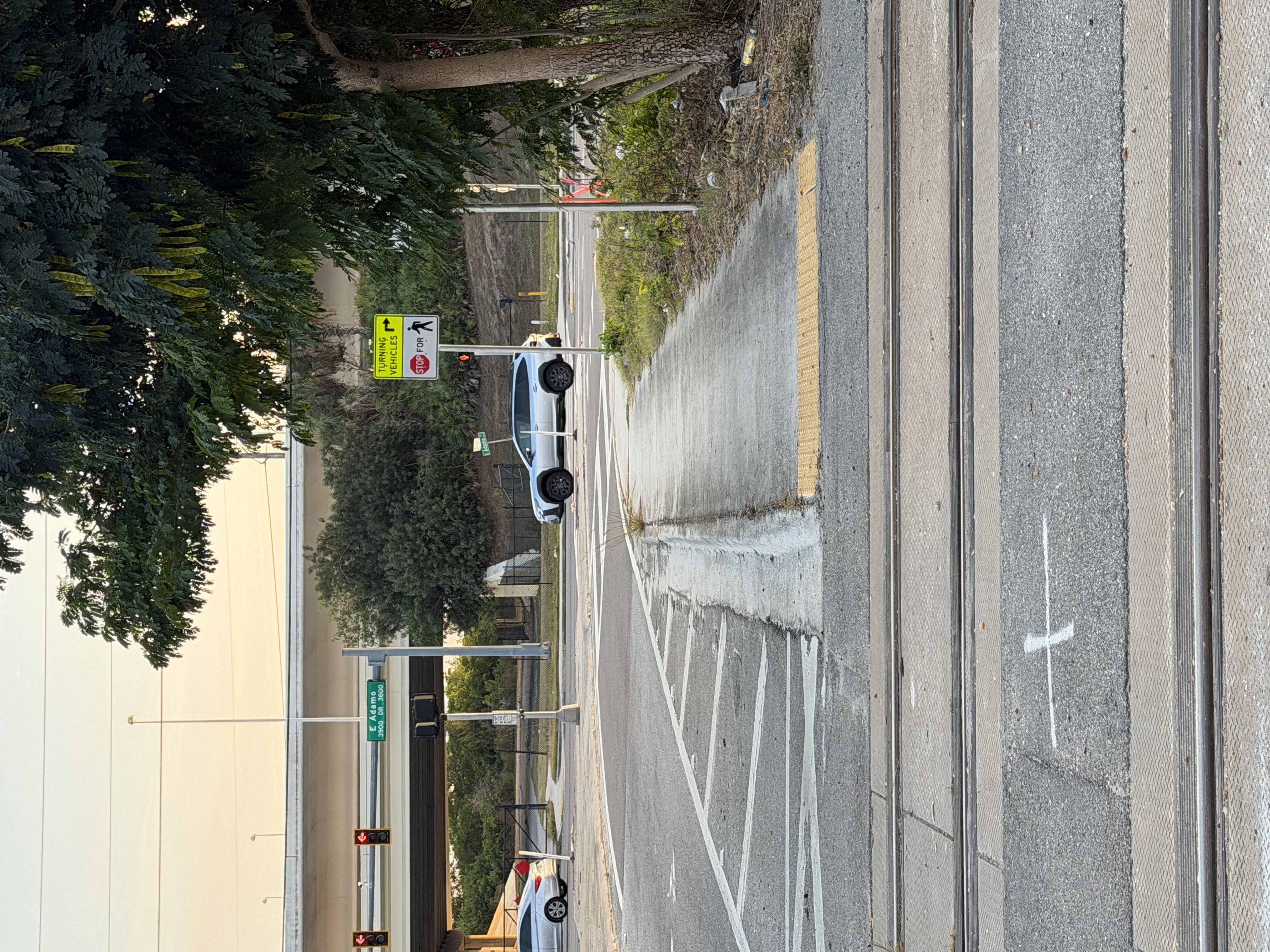 Rail crossing at dusk with pedestrian path and highway overpass