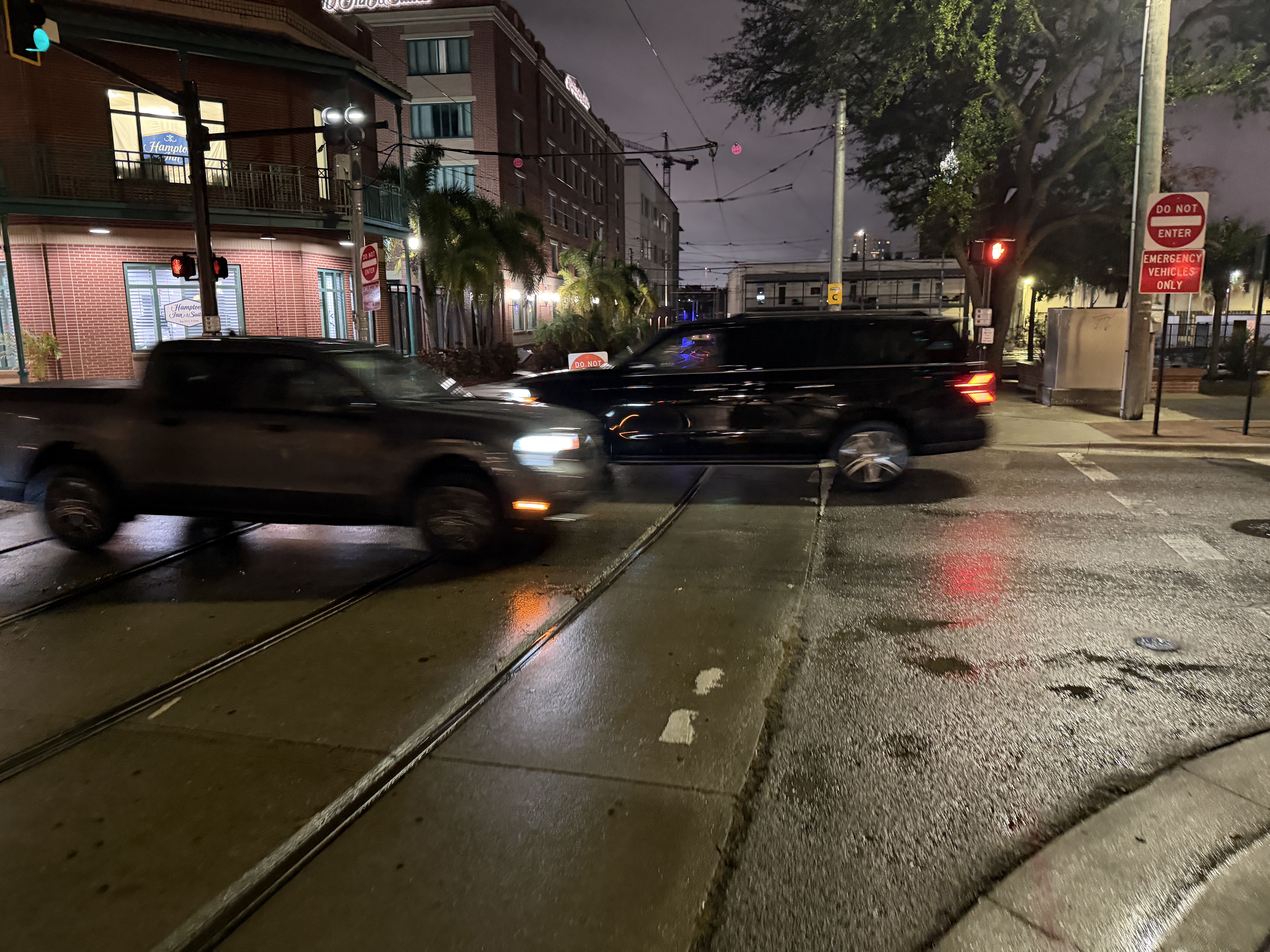 Night scene at urban rail crossing with vehicles crossing tracks and red signals active